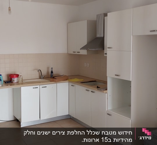 מטבח עם ארונות לבנים, כיור וברז, חומרי ניקוי על השיש